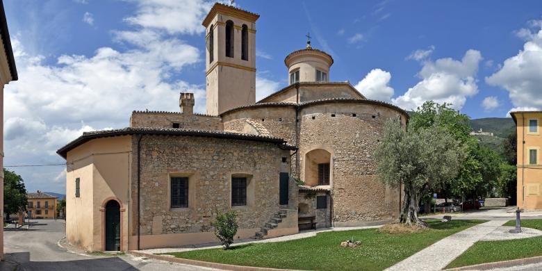 Immagine: Church of Madonna della Bianca seen from the back, with its bell tower and rounded apse, set within the village of La Bianca 